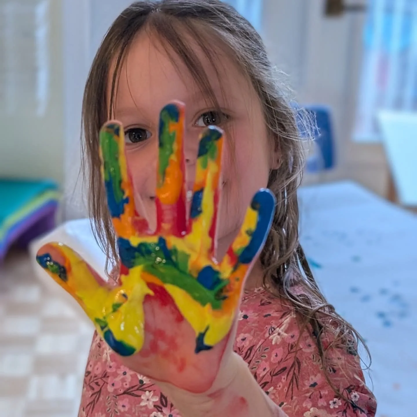 Enfant présentant sa main couverte de peinture colorée pendant une activité d’arts plastiques