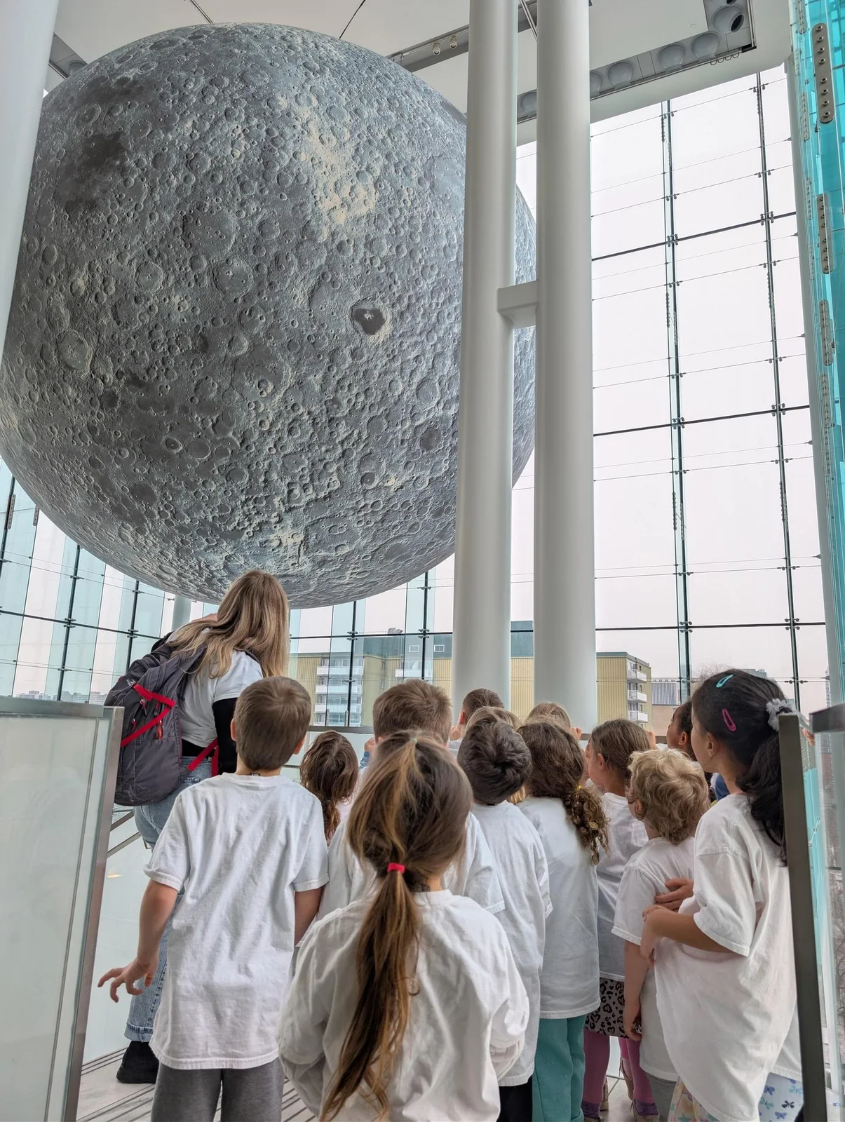 Groupe d’enfants de La petite école découvrant une reproduction géante de la Lune lors d’une sortie éducative