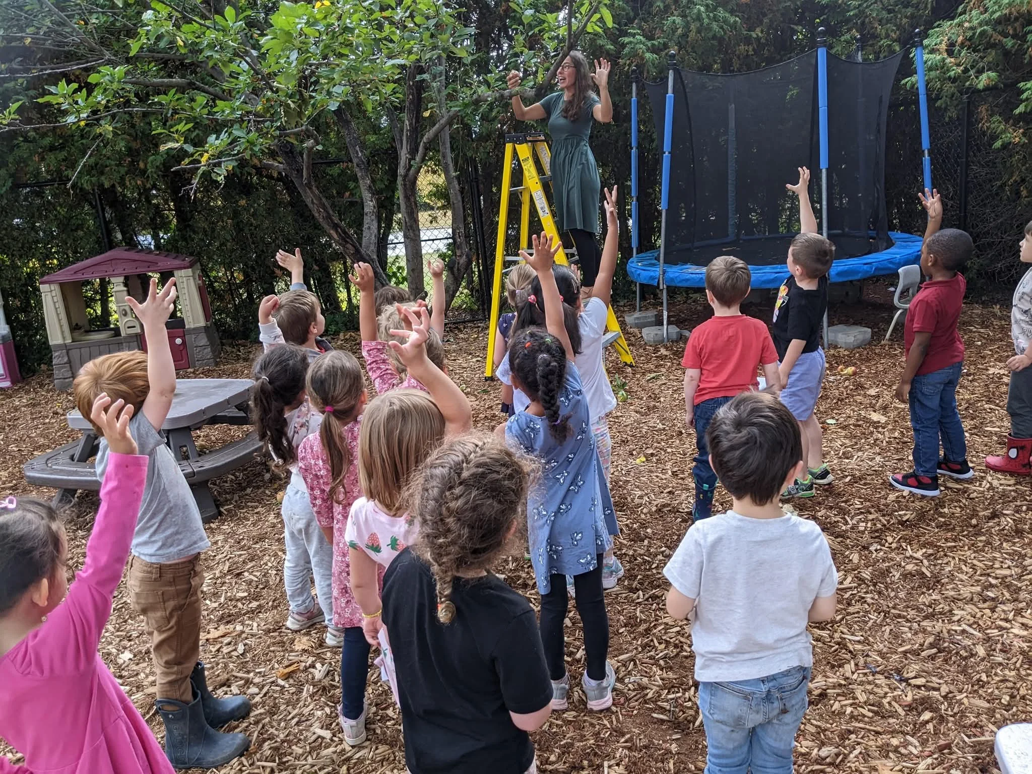 Groupe d’enfants participant à une activité extérieure avec une éducatrice dans la cour de La petite école