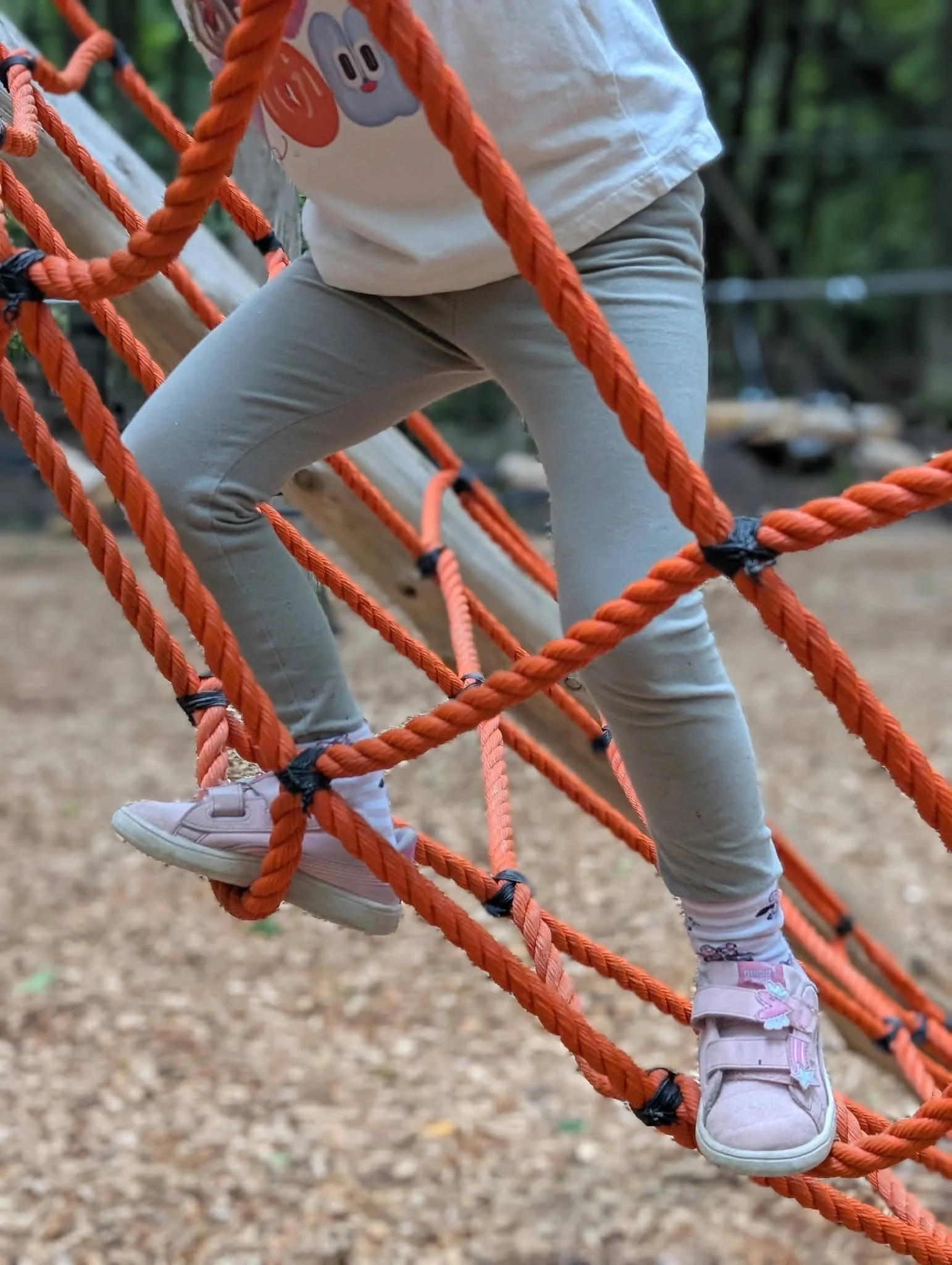 Enfant avançant sur un parcours de corde orange en forêt