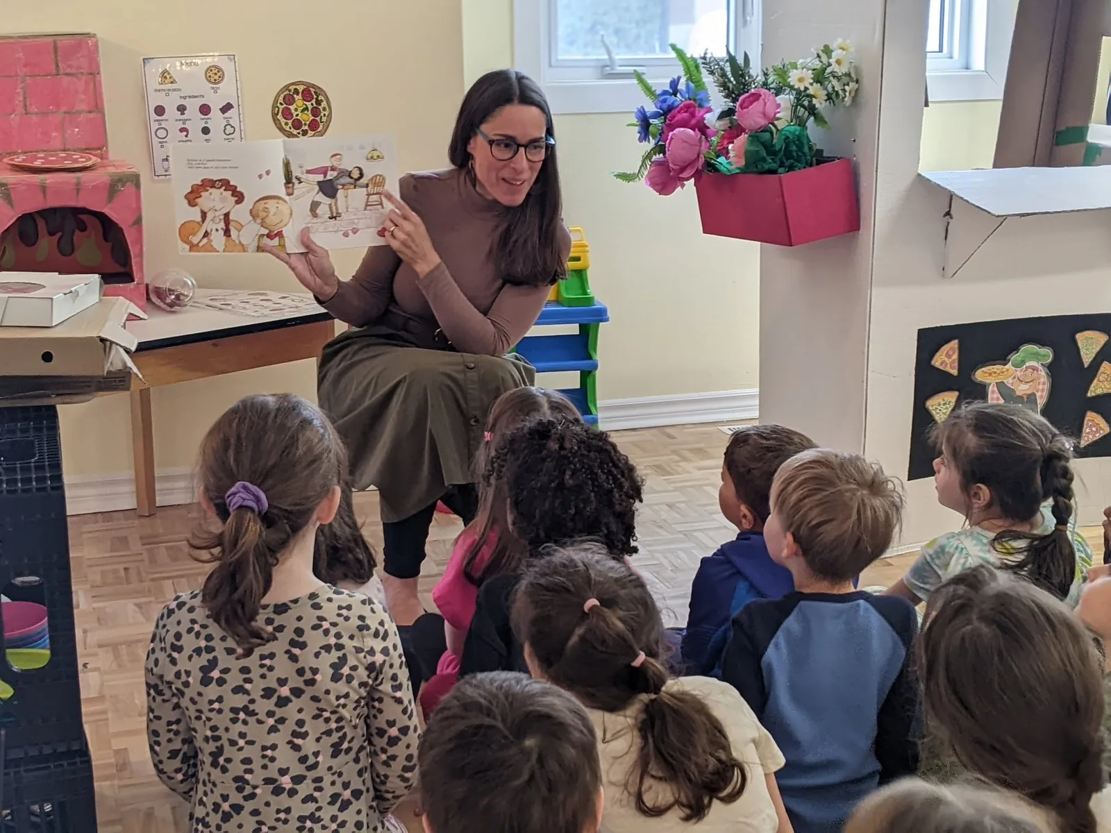 Julie présentant un livre à un groupe d’enfants de La petite école